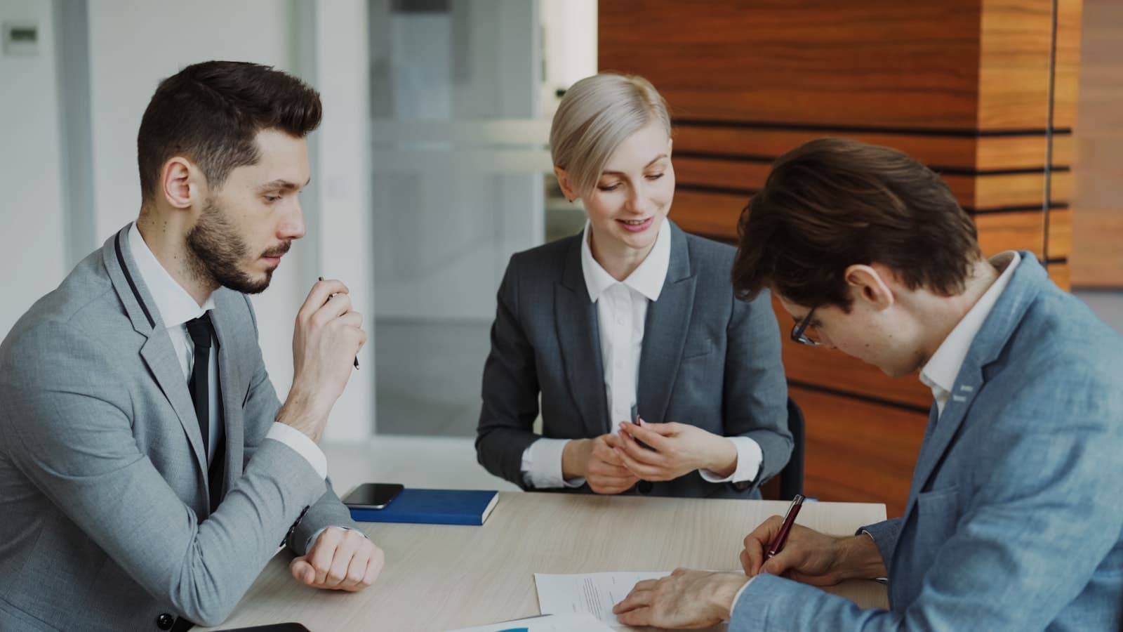 Business owners and an adviser discussing a signed agreement