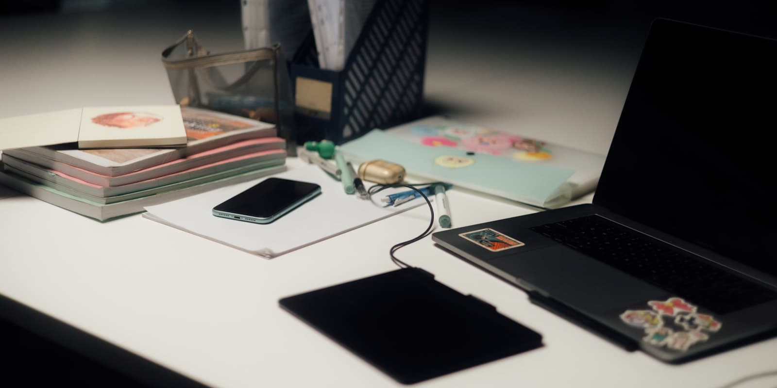 Cluttered office desk with laptop, phone and unfinished paperwork